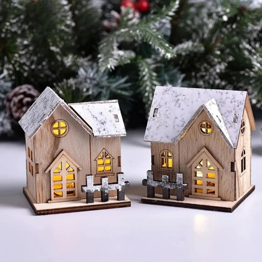 Two wooden Christmas cottage lights glowing warm in front of pine branches