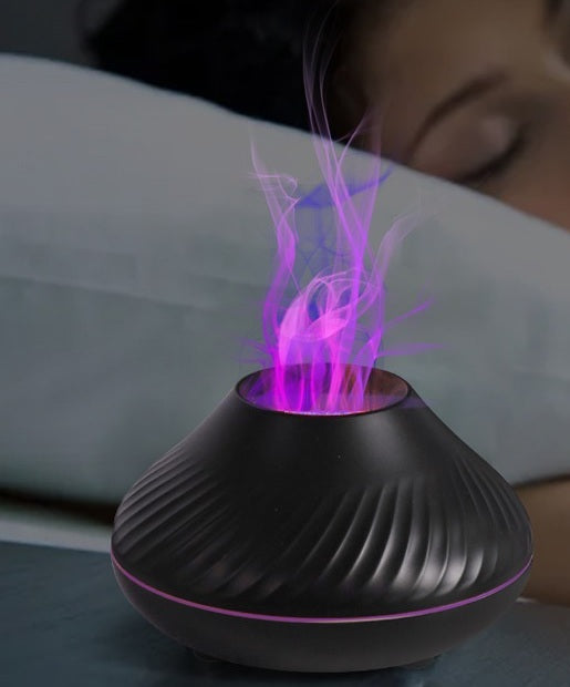 Black flame aroma diffuser glowing beside a bed at night