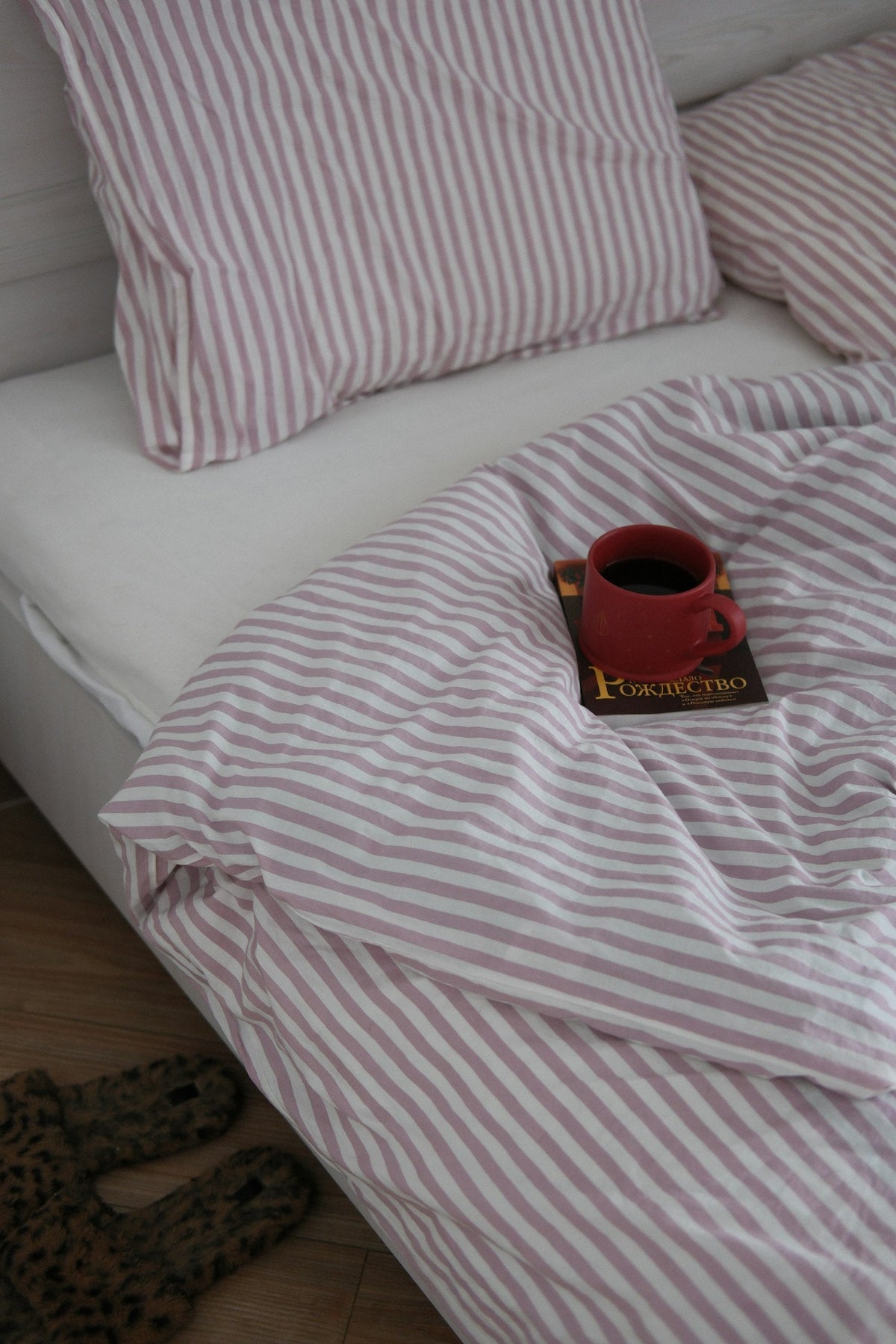 A cup of coffee resting on a book in bed
