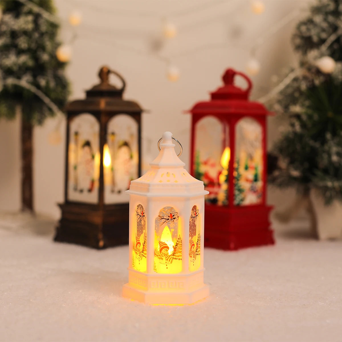 Bronze, red and white Christmas scene lanterns glowing warm on a snowy table