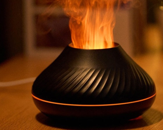 Black flame aroma diffuser with an orange flame effect on a wooden desk
